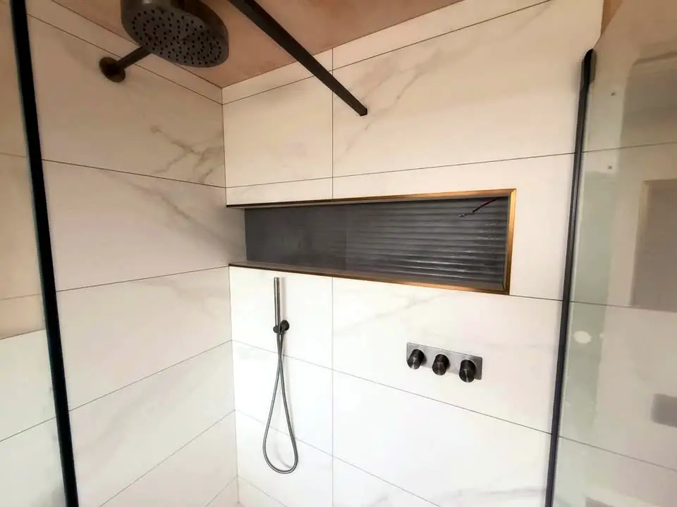 Large-format tiles with a brass-trimmed niche